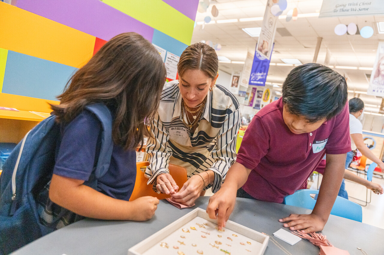 Joy helping children pick out pendants and pairing them with chains to gift one-of-a-kind jewelry to their moms for Mother's Day.