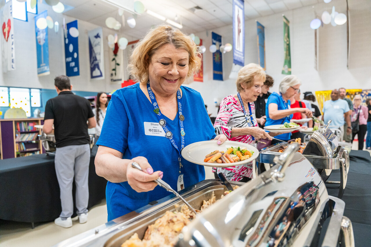 A volunteer plates up food at the luncheon.