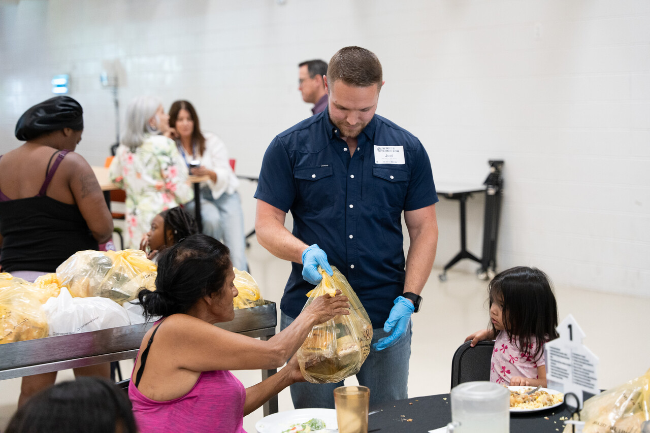 Joel Malkin hands out food to guests at Family Evening Meal.